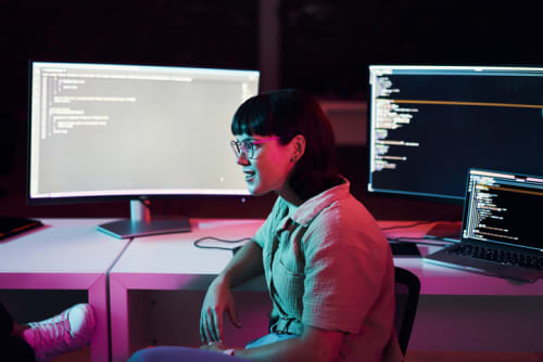 Female software engineer at her desk with two monitors