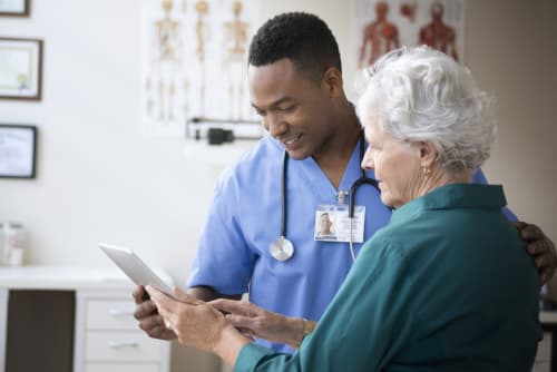 Male nurse reviewing information with elderly female patient.