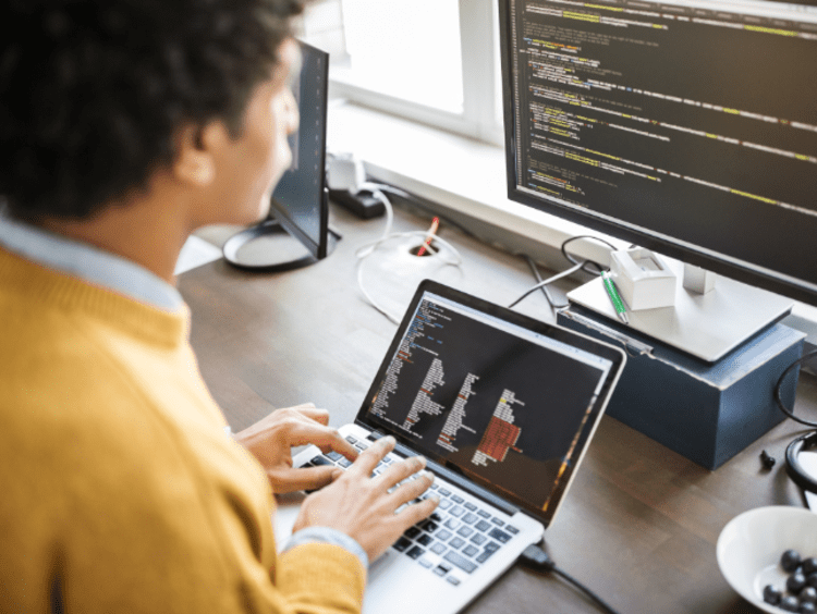 Man looking at two computer screens with code