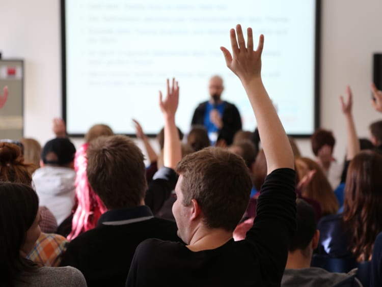 honors students raising their hands in class