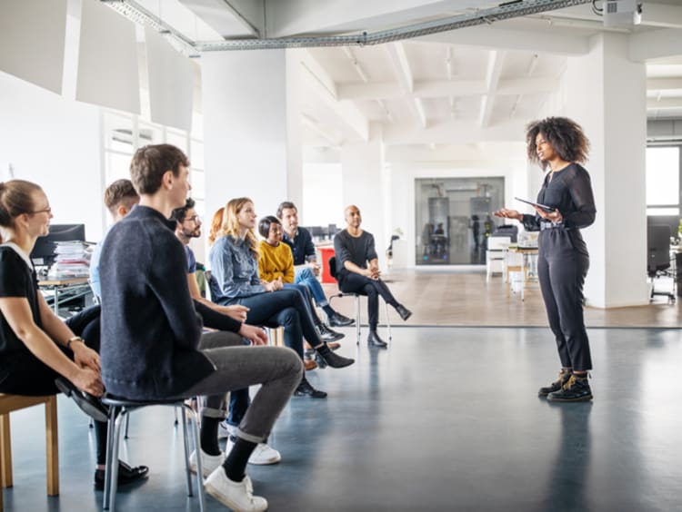 Woman speaker addressing audience in open office