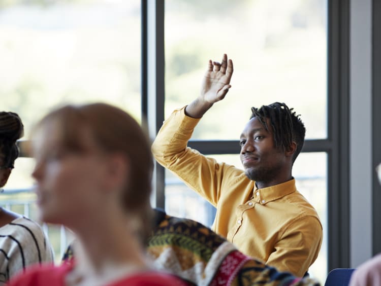 college student raising his hand in class