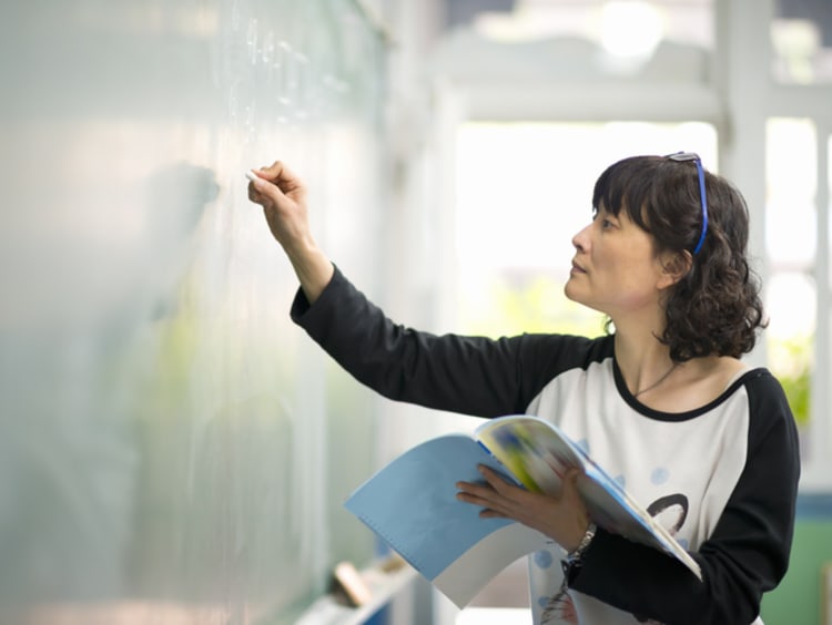 teacher writing on a chalkboard in the classroom