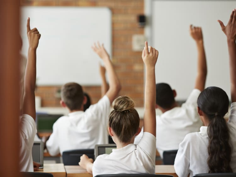 diverse students raising hands in charter school