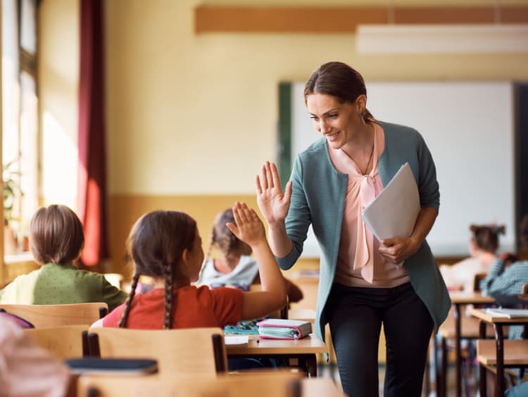 Female teacher high-fiving a student