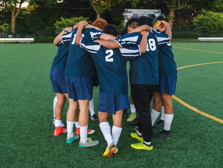 college soccer players having a team huddle before game