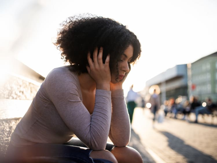 Young woman sitting alone in a sad state of mind.