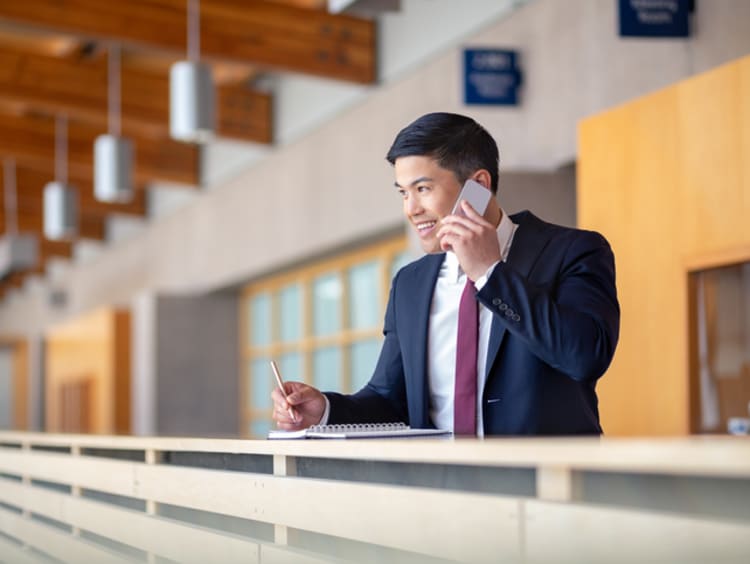 Young political science student taking notes on a phone call.
