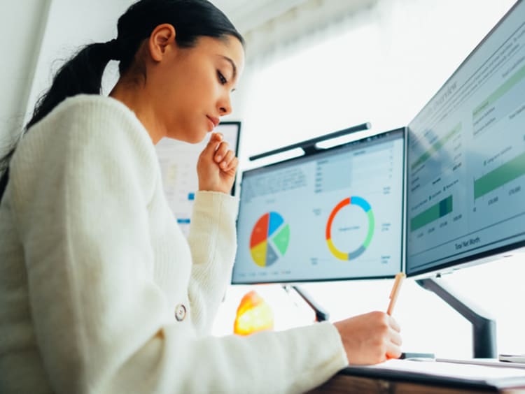 Woman looking at financial charts on computer screens
