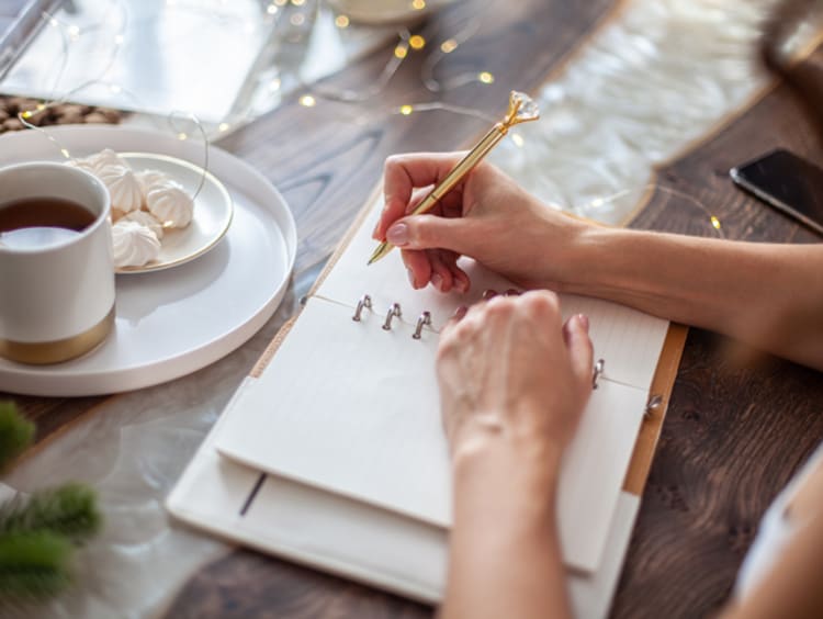 Young woman sitting with coffee and journaling her goals
