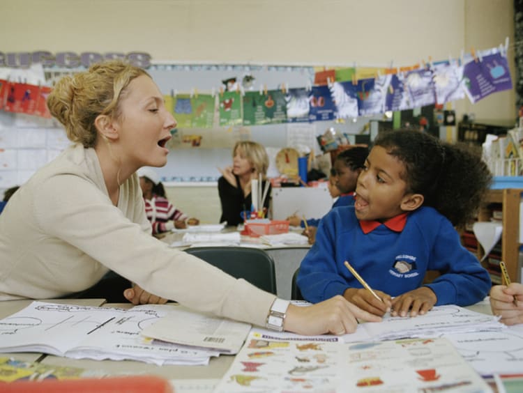 teacher helping young student pronounce words