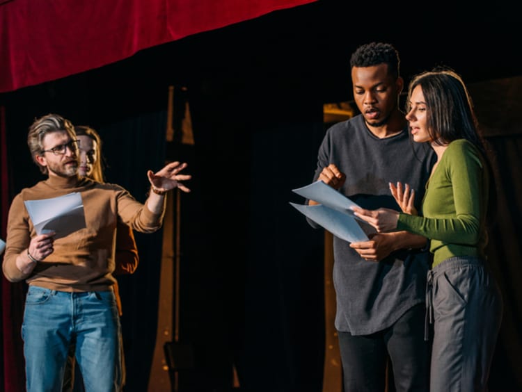 Theater director, multicultural actors and actress rehearsing on stage - stock photo