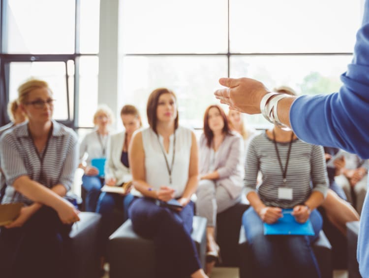 Corporate trainer giving speech and training group