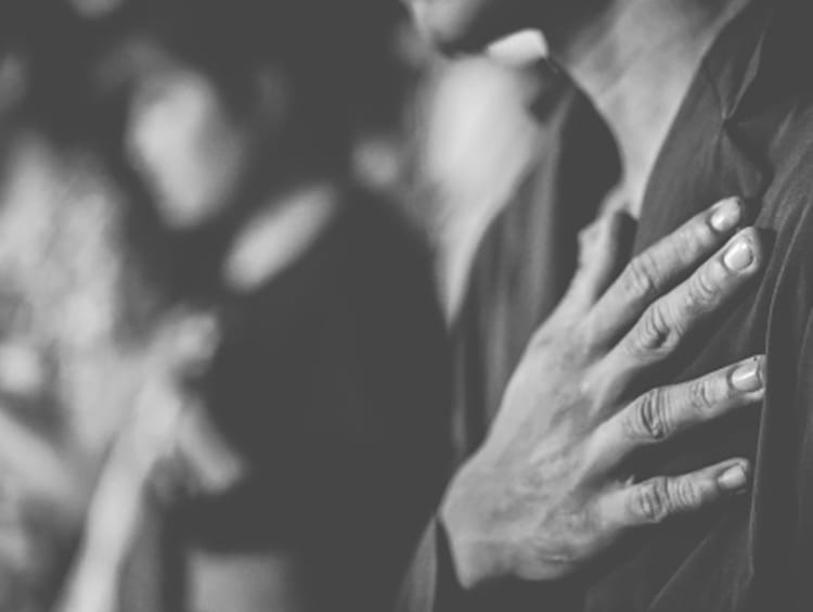 Man in suit with his hand over his heart in prayer.