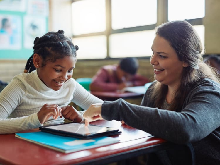 Teacher helping young student with tablet