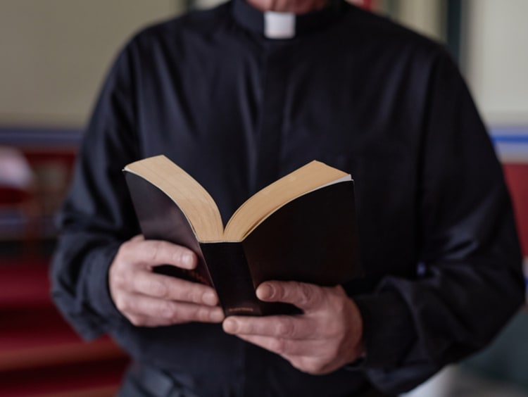 Close-up of priest reading Bible book during ceremony standing near the altar in church