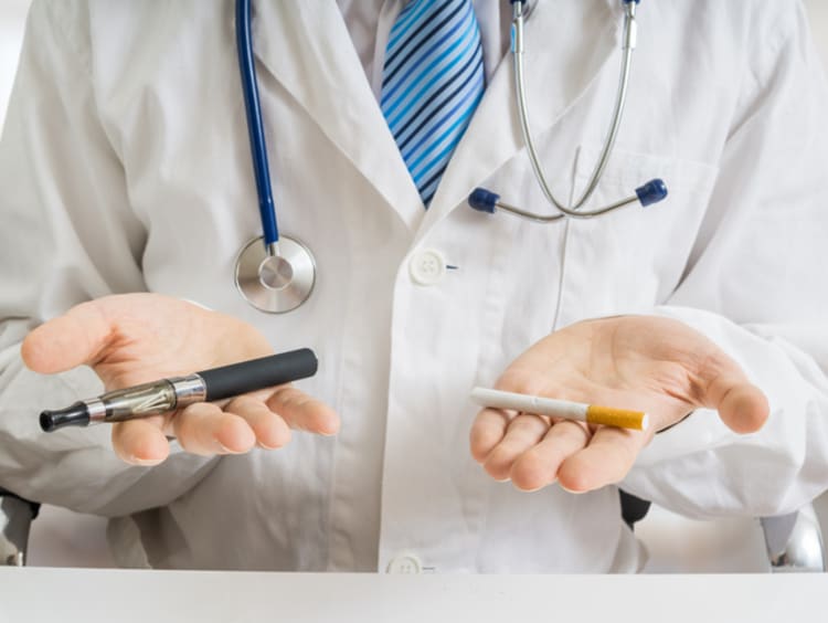 Doctor is comparing electronic vaporizer and conventional tobacco cigarette. - stock photo