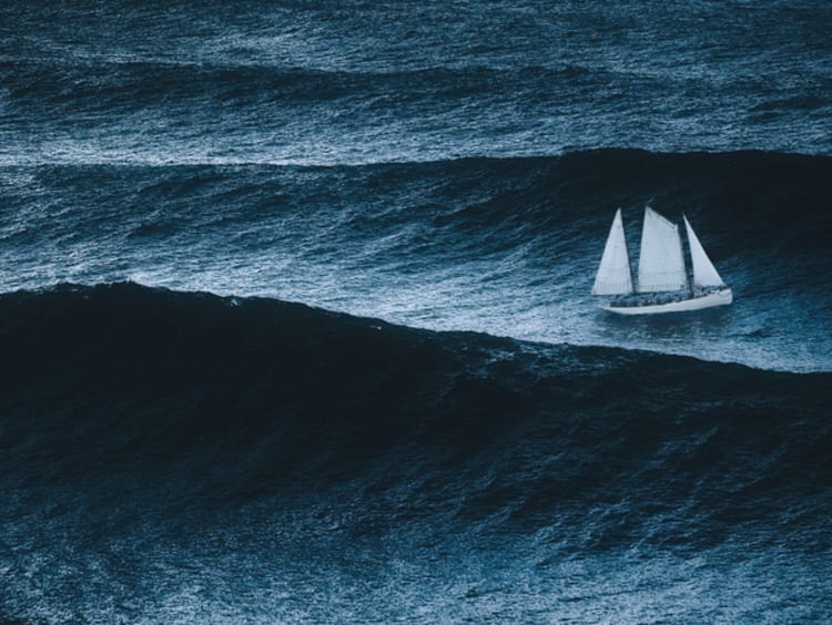 White sailboat sailing on large waves