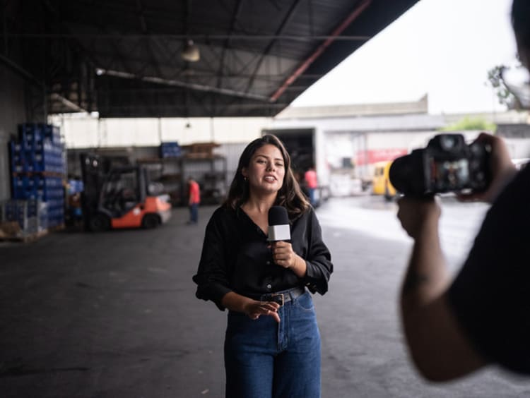 Young female broadcast journalist reporting on location