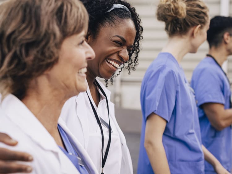 Female nurses laughing with arms around each other