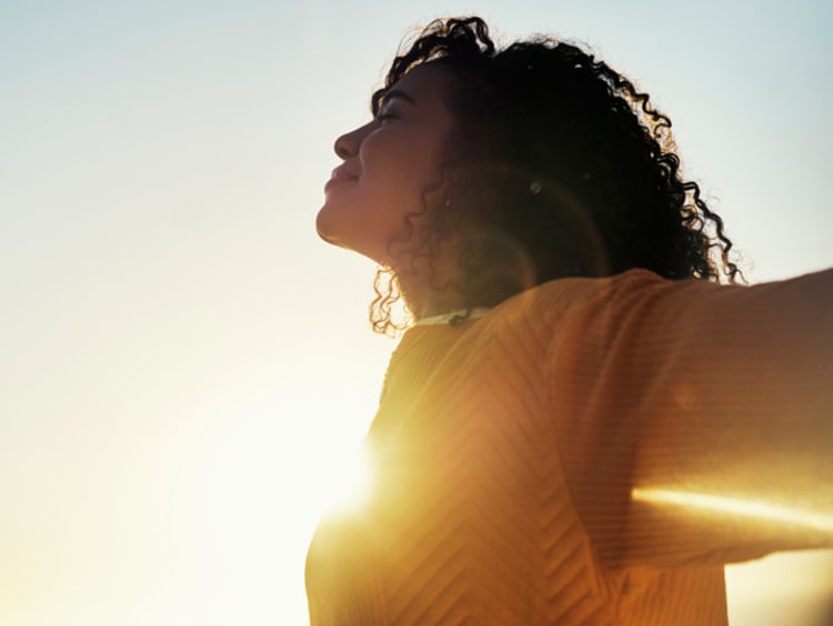 Woman outdoors with arms stretched wide smiling
