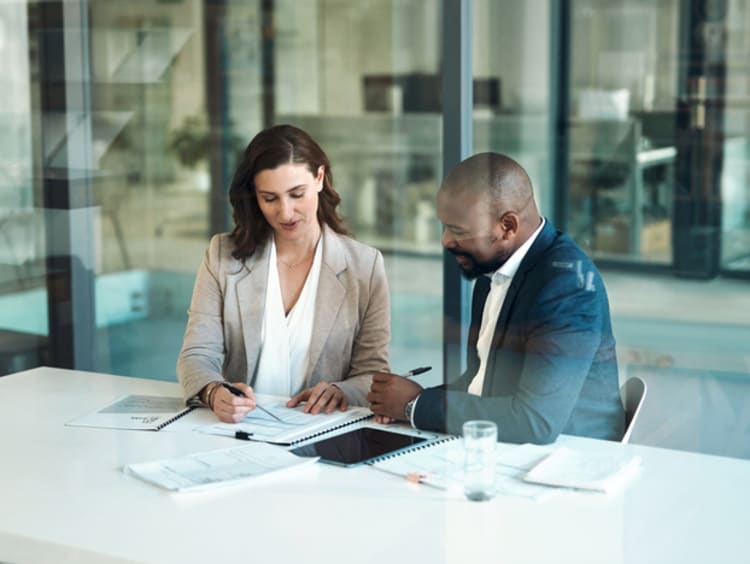 man and women sitting in office going over paperwork and finances