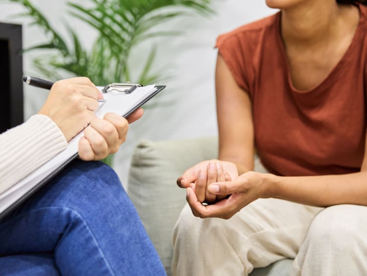 Close up of counselor writing on clipboard while with patient