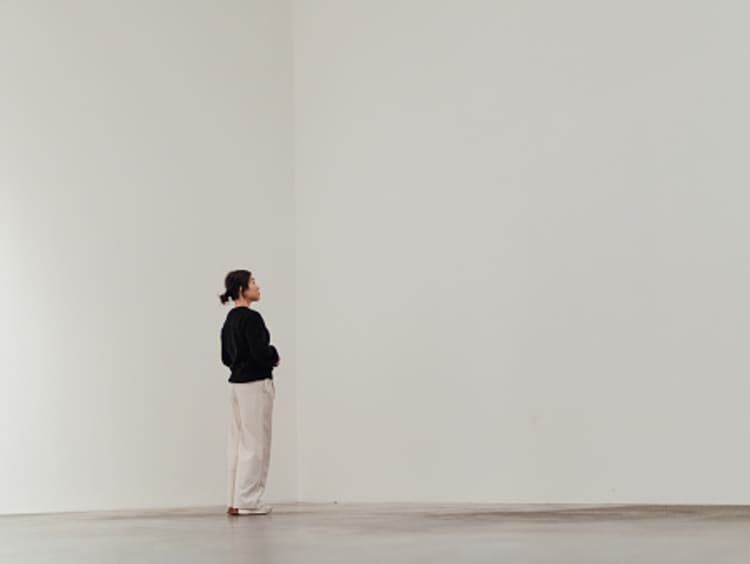 A simple white room with a Woman wandering.