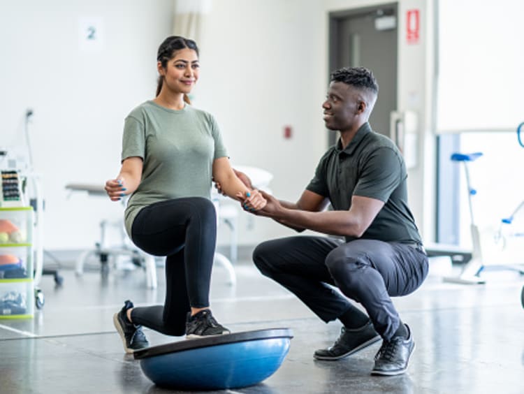Male Physical therapist assisting a female patient.