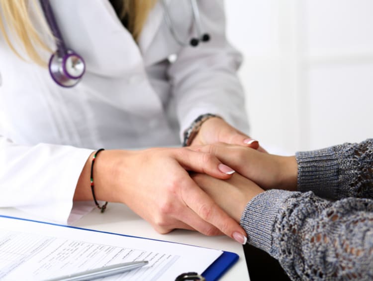 Friendly female doctor hold patient hand in office during reception. Examination result, positive test, calm down, promise and cheer up, grief and suffer, treatment, condolence, ethics concept