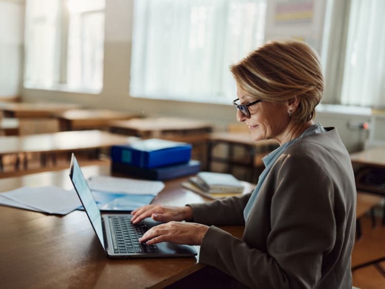 teacher working on laptop in an empty classroom