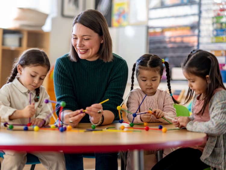 Teacher smiling while helping students in classroom