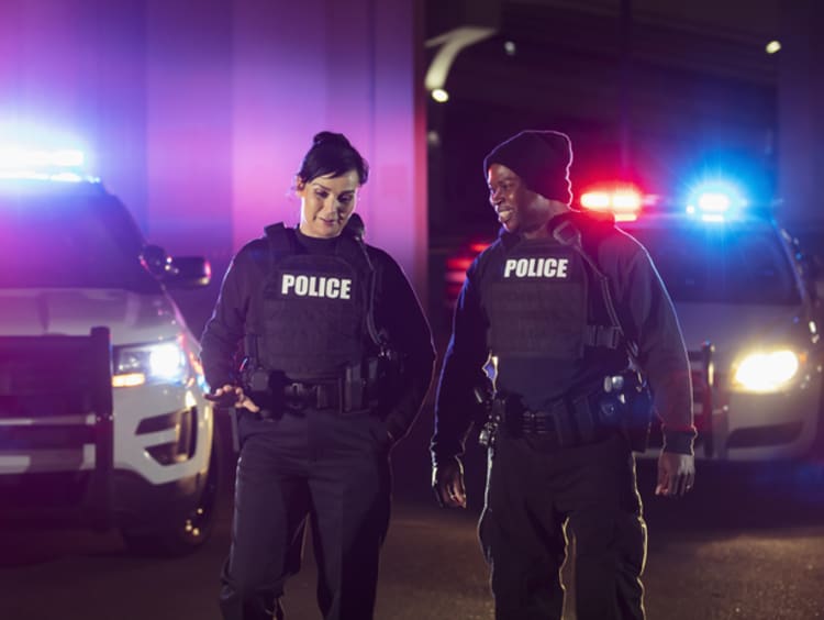Police officers talking and walking near police cars