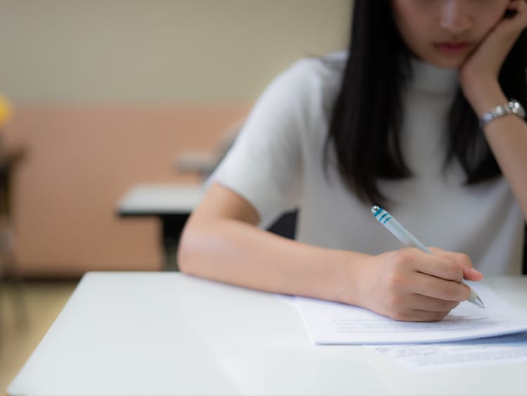 School student's taking exam writing answer in classroom for education and literacy concept - stock photo
