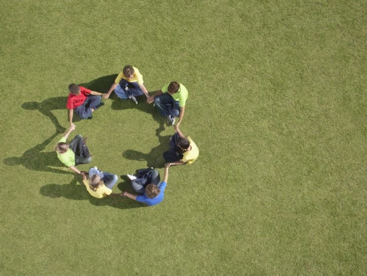 Group of children sitting on grass in circle formation - stock photo