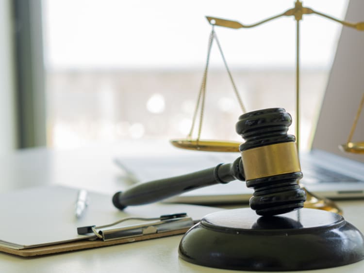 A desk with justice scales, a wooden gavel, and papers