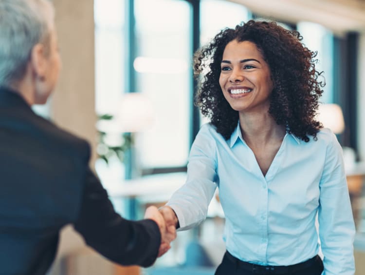 business women smiling while shaking hands after earning degree from GCU