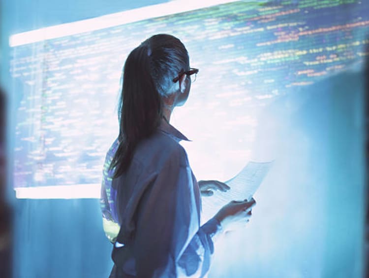 Woman working on a programming project being projected on a screen.