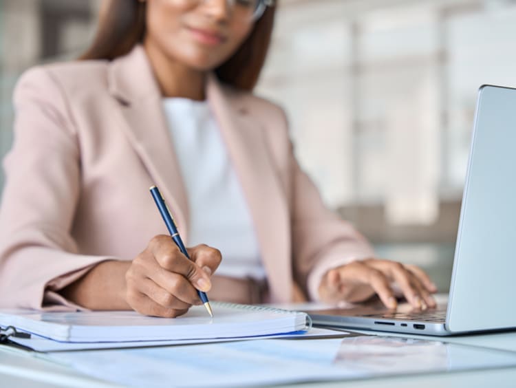 woman in office writing in notebook