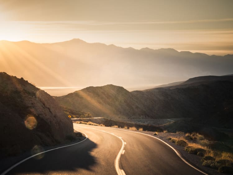 Highway at sunrise, going into Death Valley National Park - stock photo