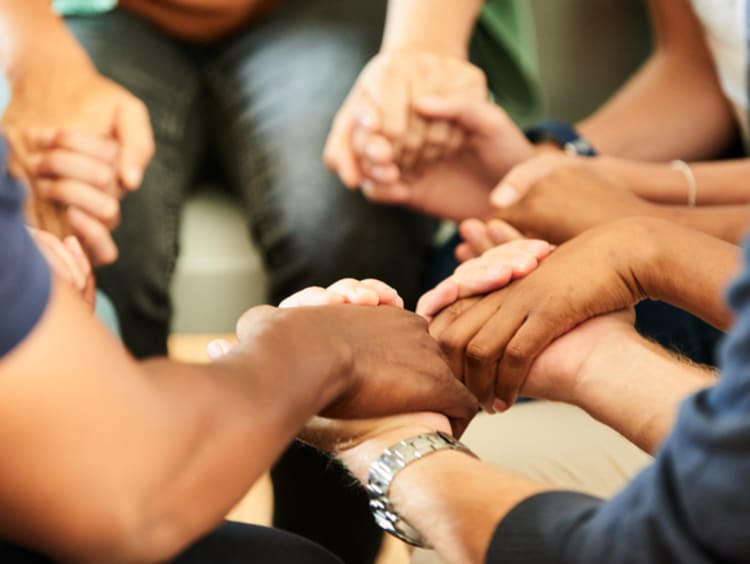 People holding hands together during a support group meeting - stock photo