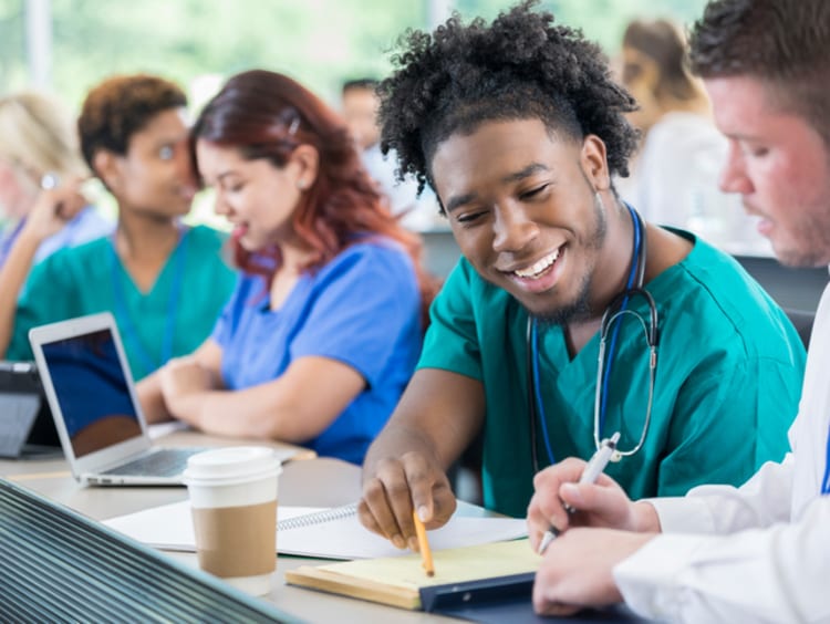 Diverse male medical students work together on project.