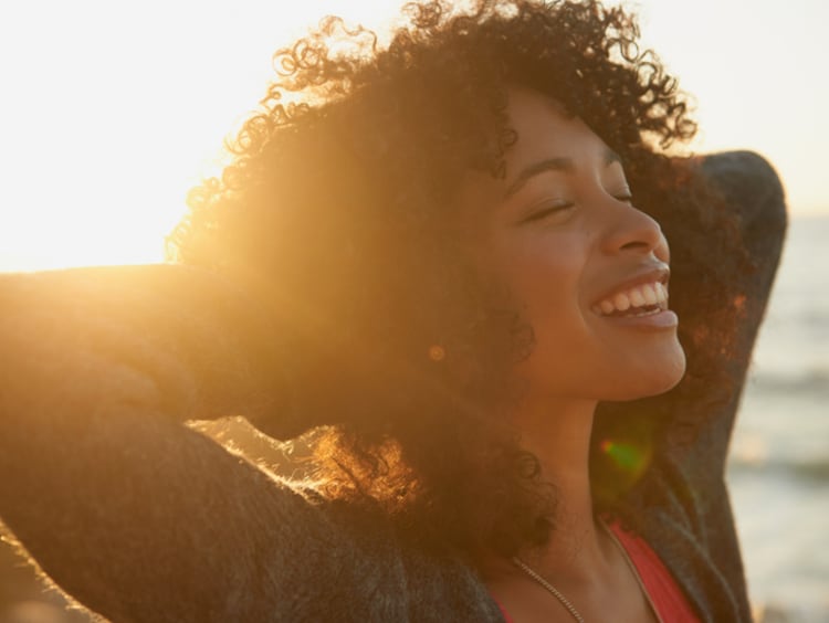 woman smiling with a sunset behind her