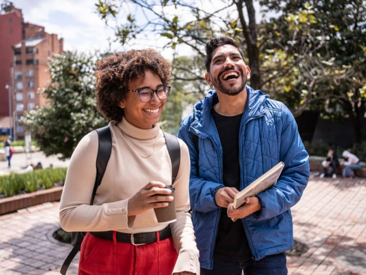 Two friends laugh together on college campus.