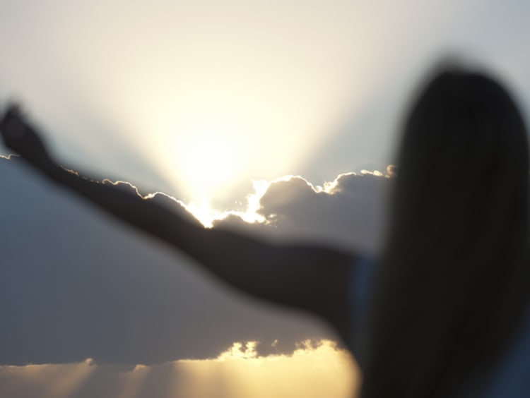 woman stretching out arms to the sky