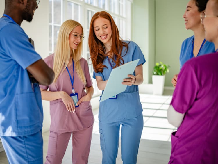 Several nurses standing around discussing a patient's chart.