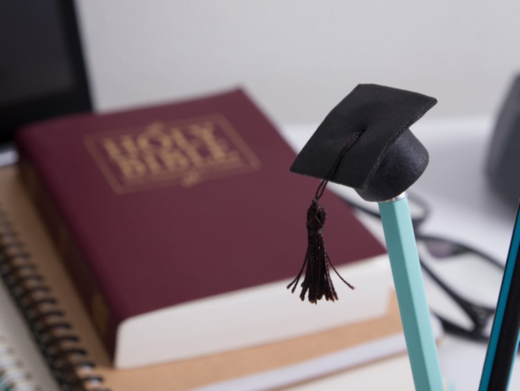 Pencil with graduation hat and q bible in the background.