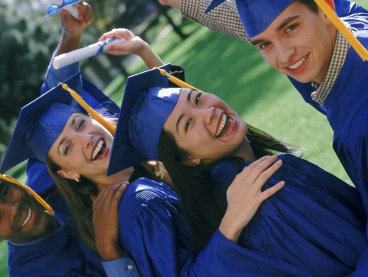 Group of students smiling in their blue cap and gown at graduation