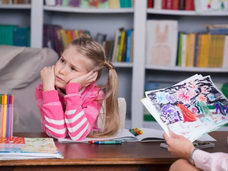 Professional child counselor looks at little girl's drawing while girl in pink looks distressed