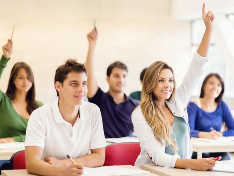 kids in classroom raising their hands